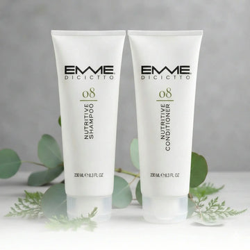 Emme Diciotto 08 Nutritive Shampoo and Conditioner tubes displayed with green eucalyptus leaves.