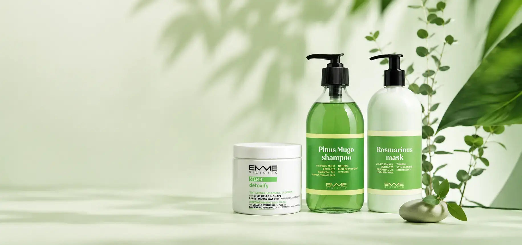 Emme Diciotto natural hair care line including STEM-C Detoxify jar, Pinus Mugo shampoo, and Rosmarinus mask set against a soft green background with leafy shadows.1621243260e1af0c20-1